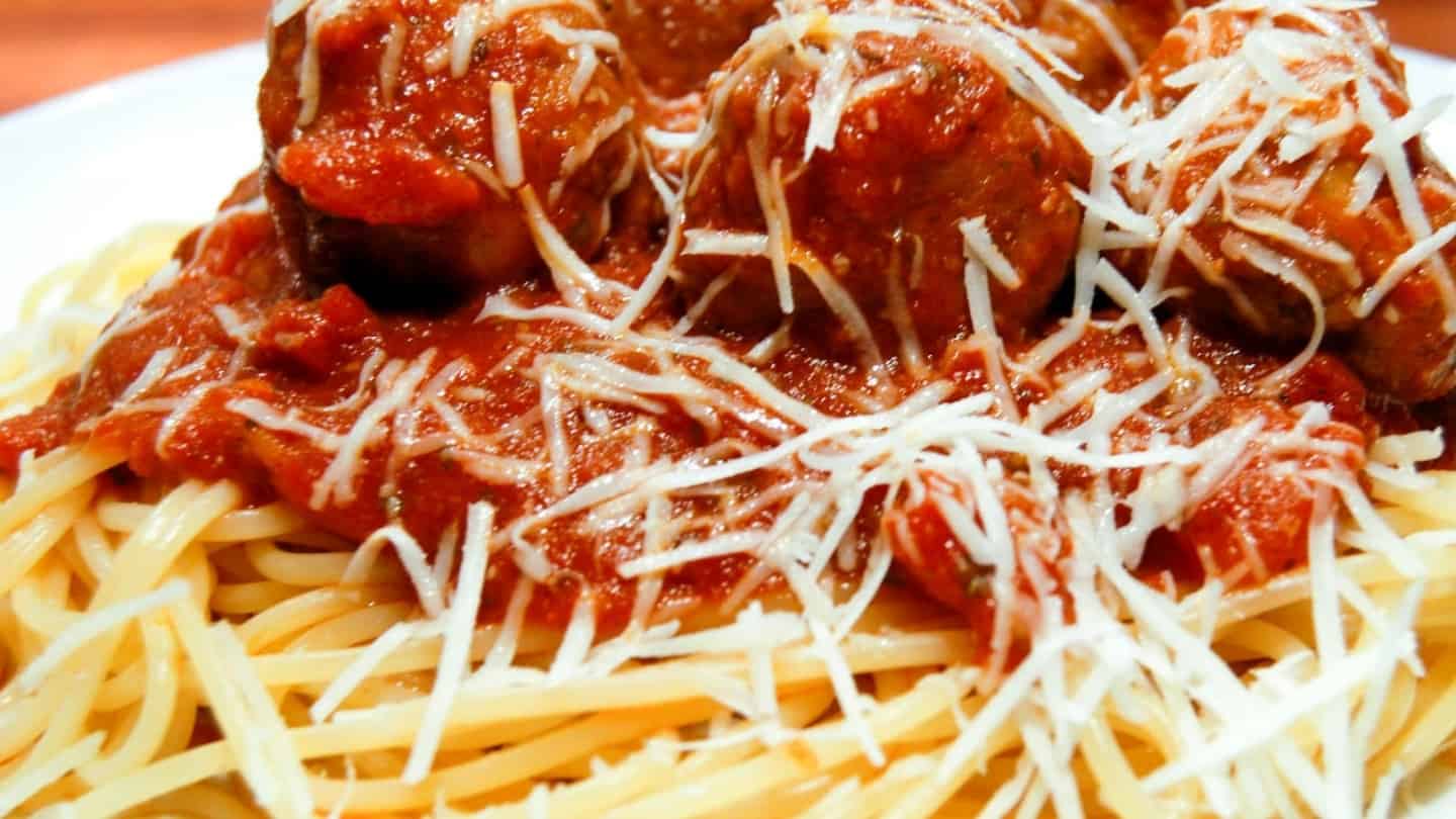 Italian marinara sauce with meat balls on top of a plate of spaghetti.