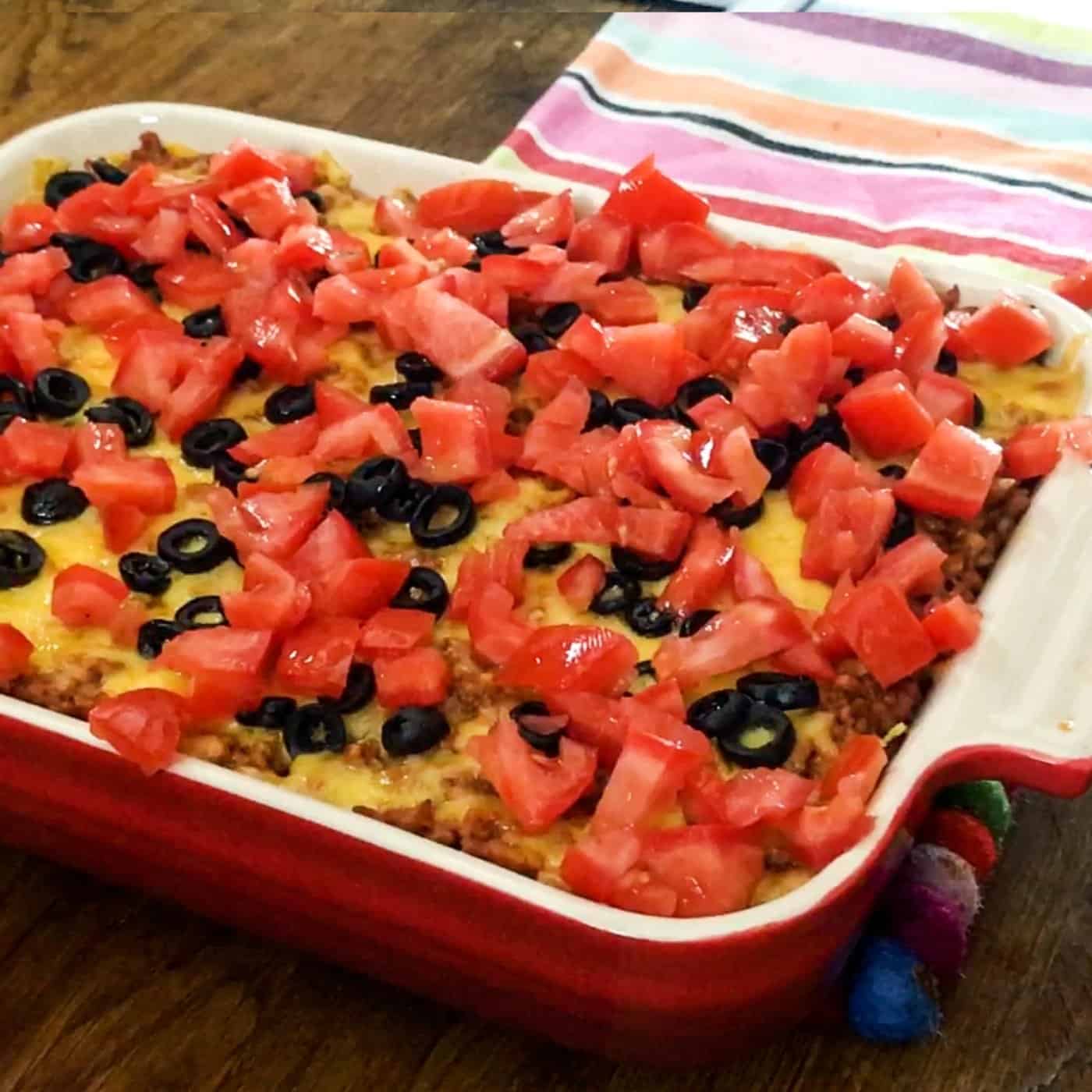 taco casserole with black olives and tomatoes on top