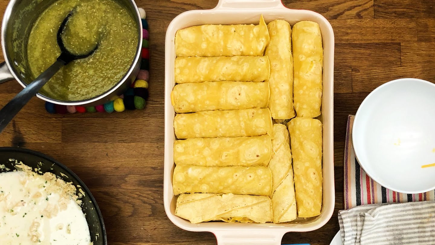 Rolling enchiladas verdes with chicken putting on a baking dish