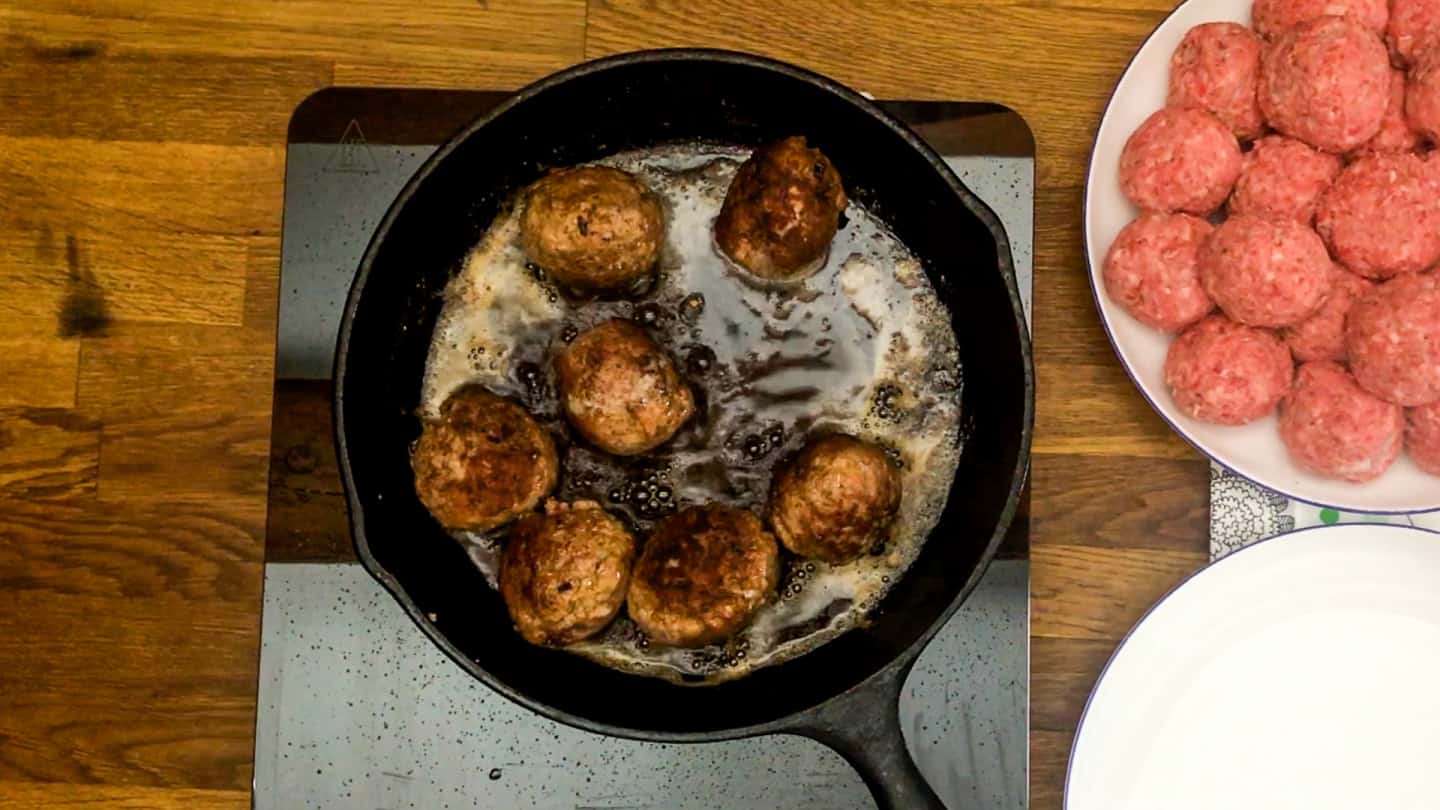 freshly made meatballs perfectly browned in large cast iron skillet