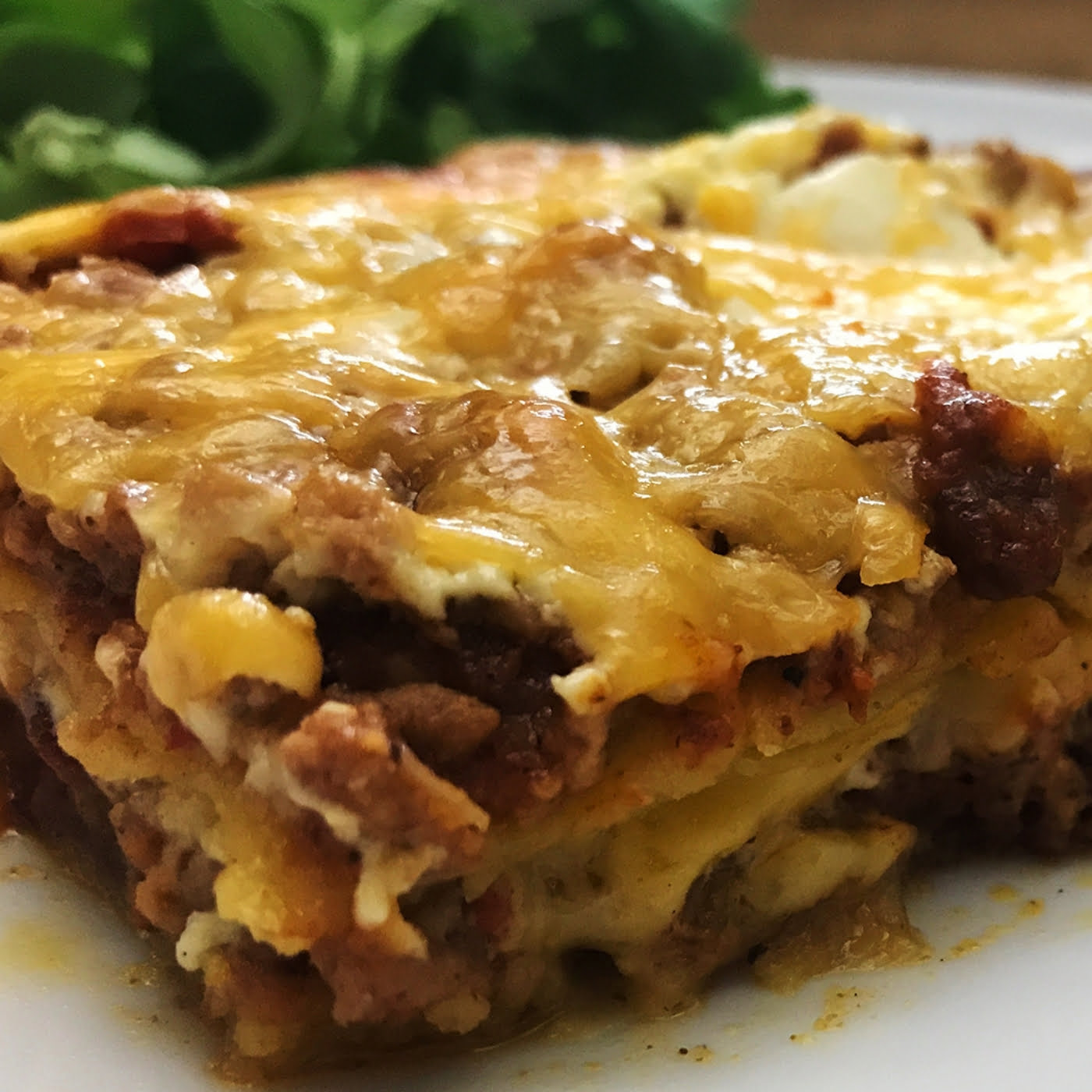 mexican lasagna loaded with a meat mixture, layered with crispy corn tortillas, and smothered with shredded cheddar cheese