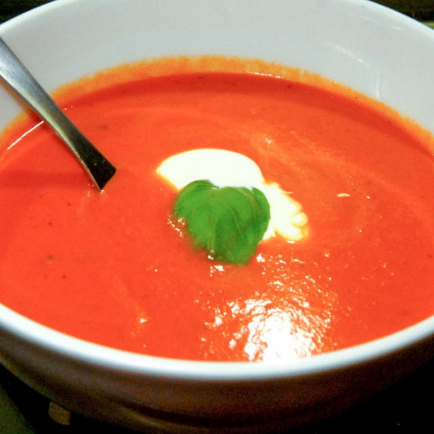 Roasted tomato soup with basil serve in a white bowl