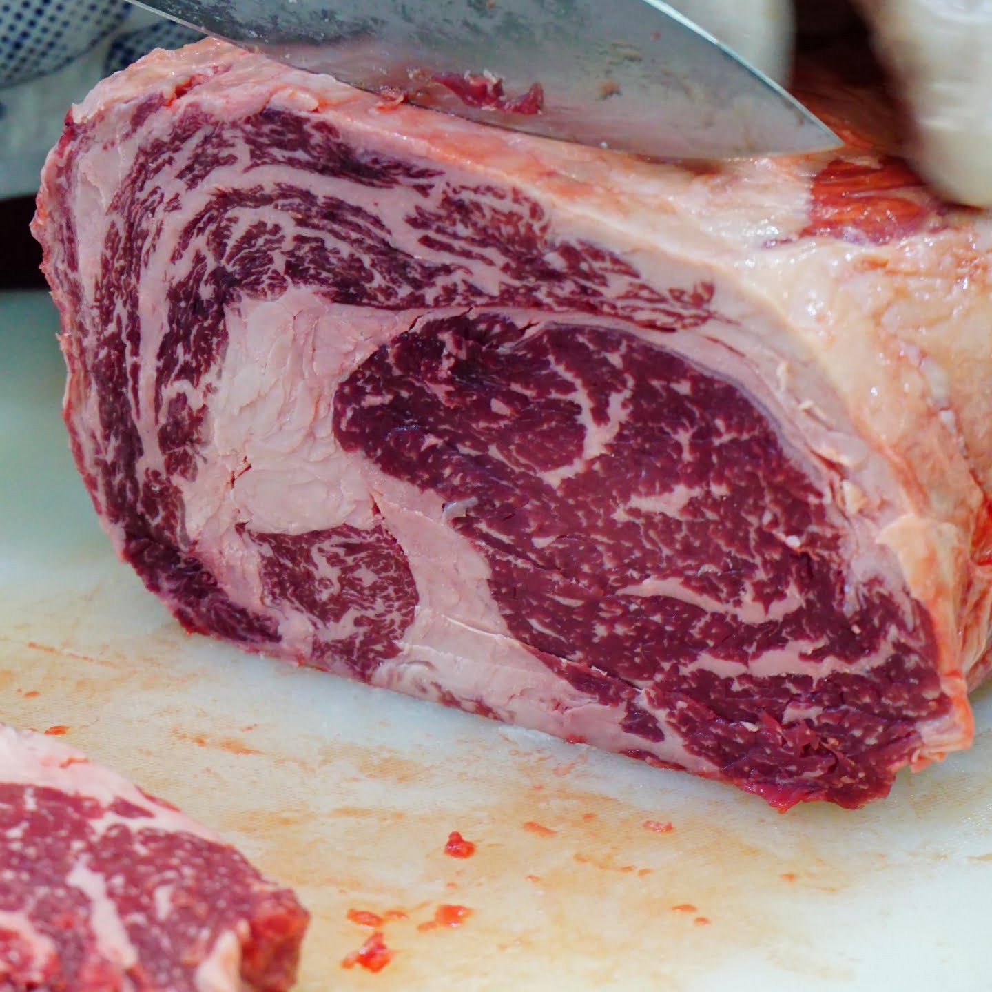 Wagyu beef sliced by the butcher. Visible extensive marbling throughout the cut of the meet.