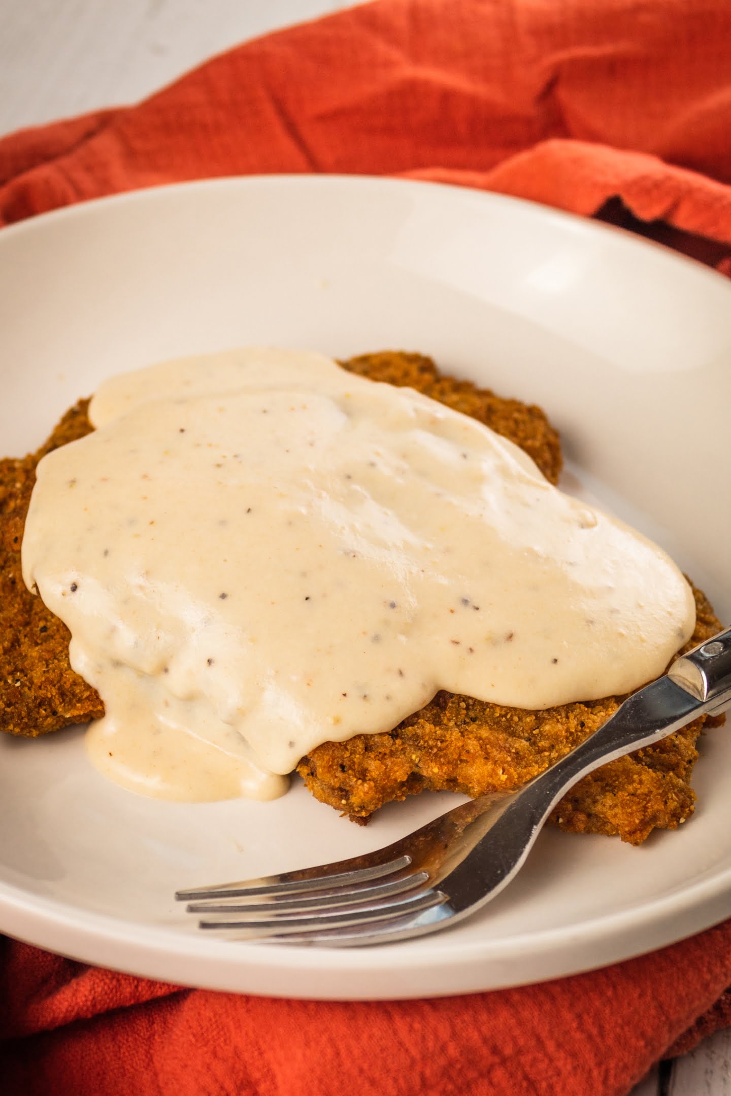 white gravy pouring  on a fried chicken 
