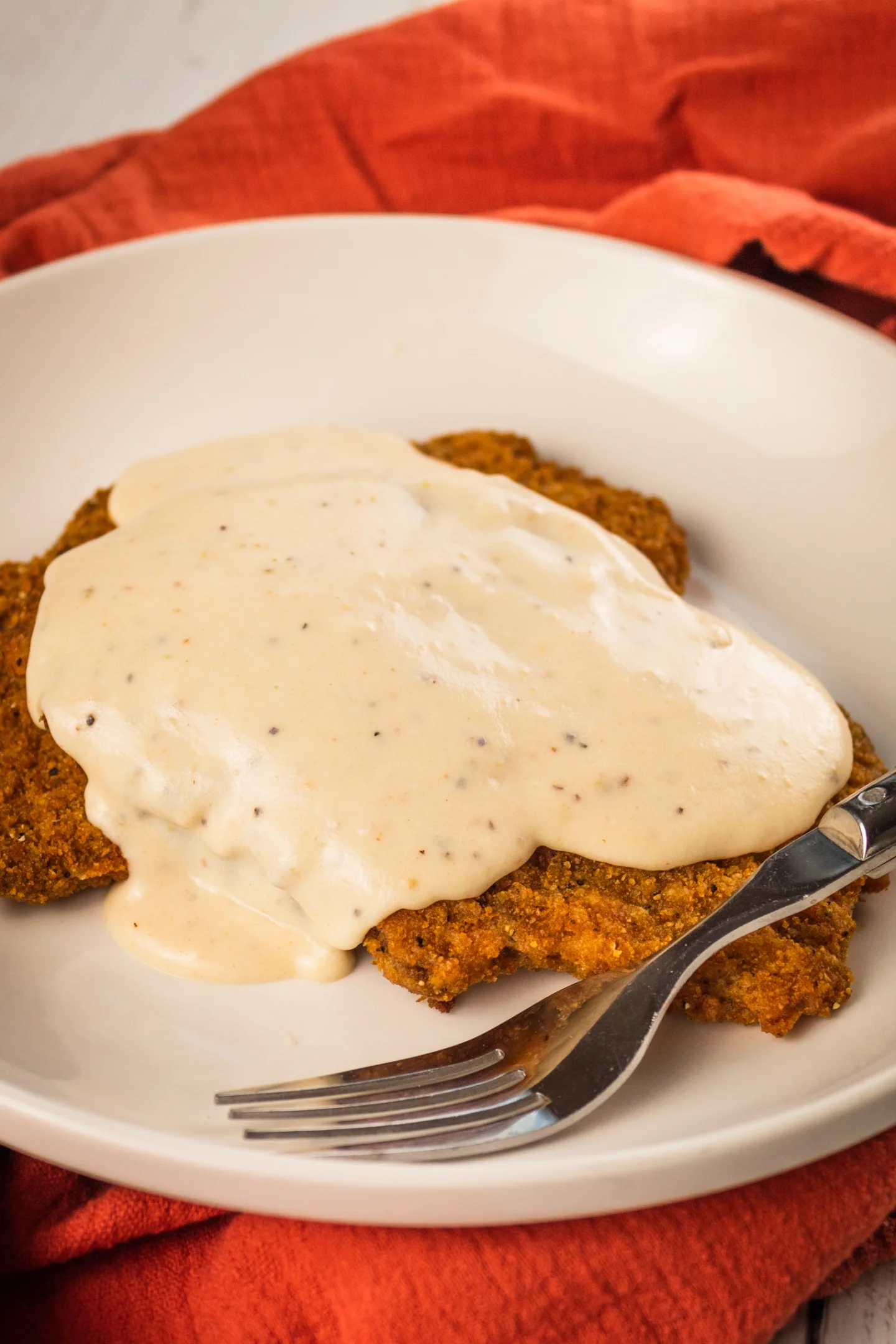 white gravy pouring  on a fried chicken 