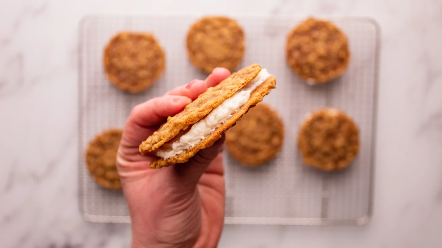 Spoon the cream filling into a piping bag with a nozzle and pipe the filling into the center of half of the cooled oatmeal cookies