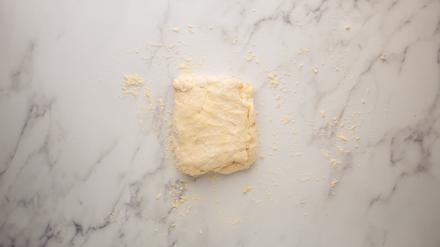 Transfer the biscuit dough to a heavily floured surface and flatten it with your hands to form a rectangle about ½ inch thick
