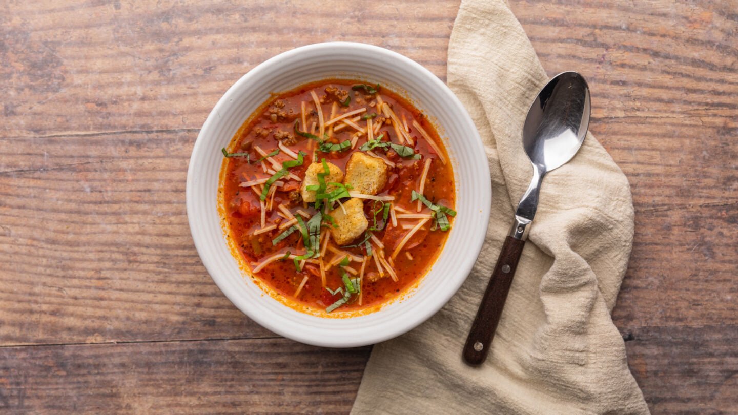 Remove the soup from the heat and ladle it into serving bowls topped with shredded cheese, fresh basil, and croutons