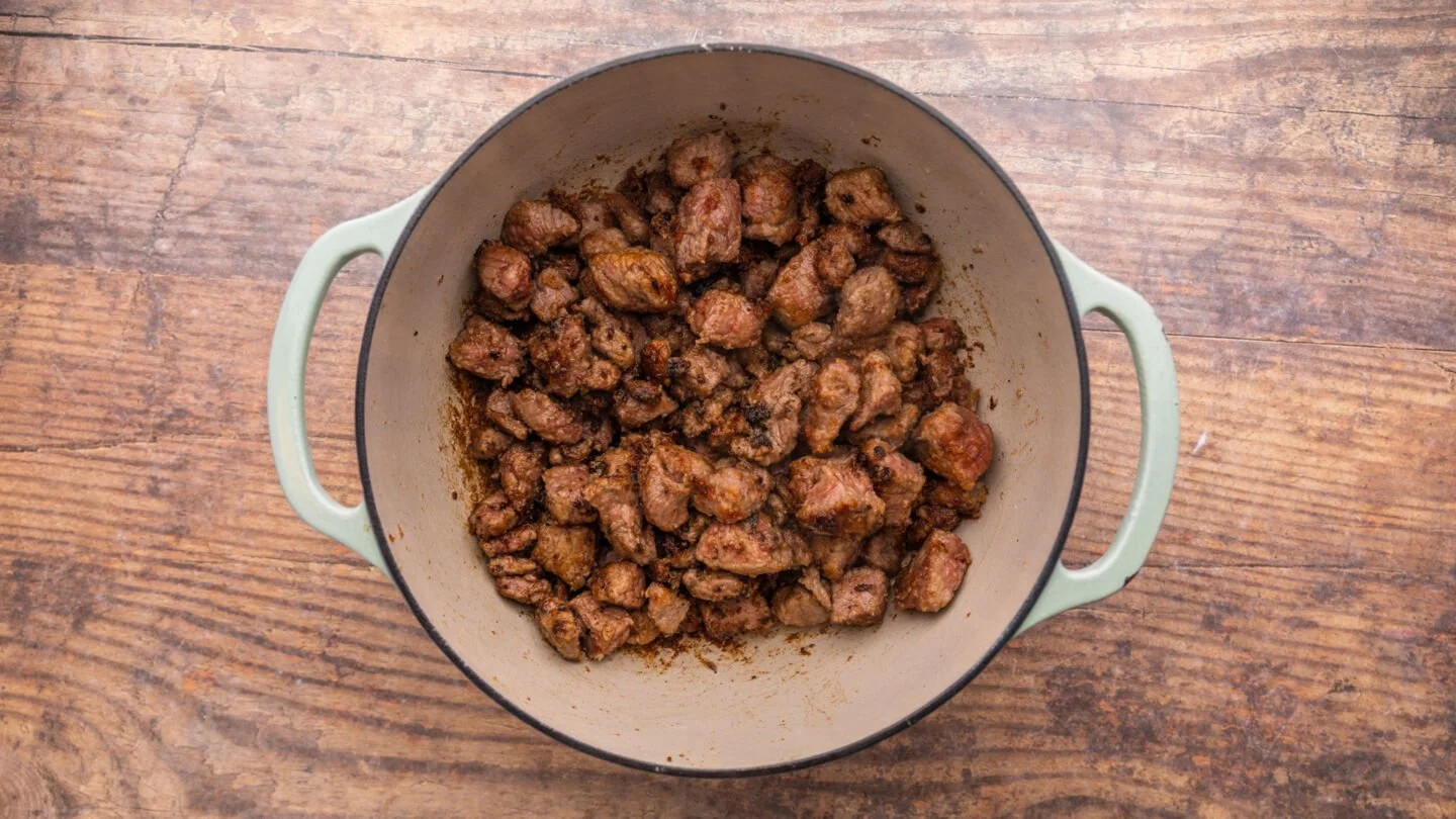 Once hot, cook the coated beef cubes until browned all over.