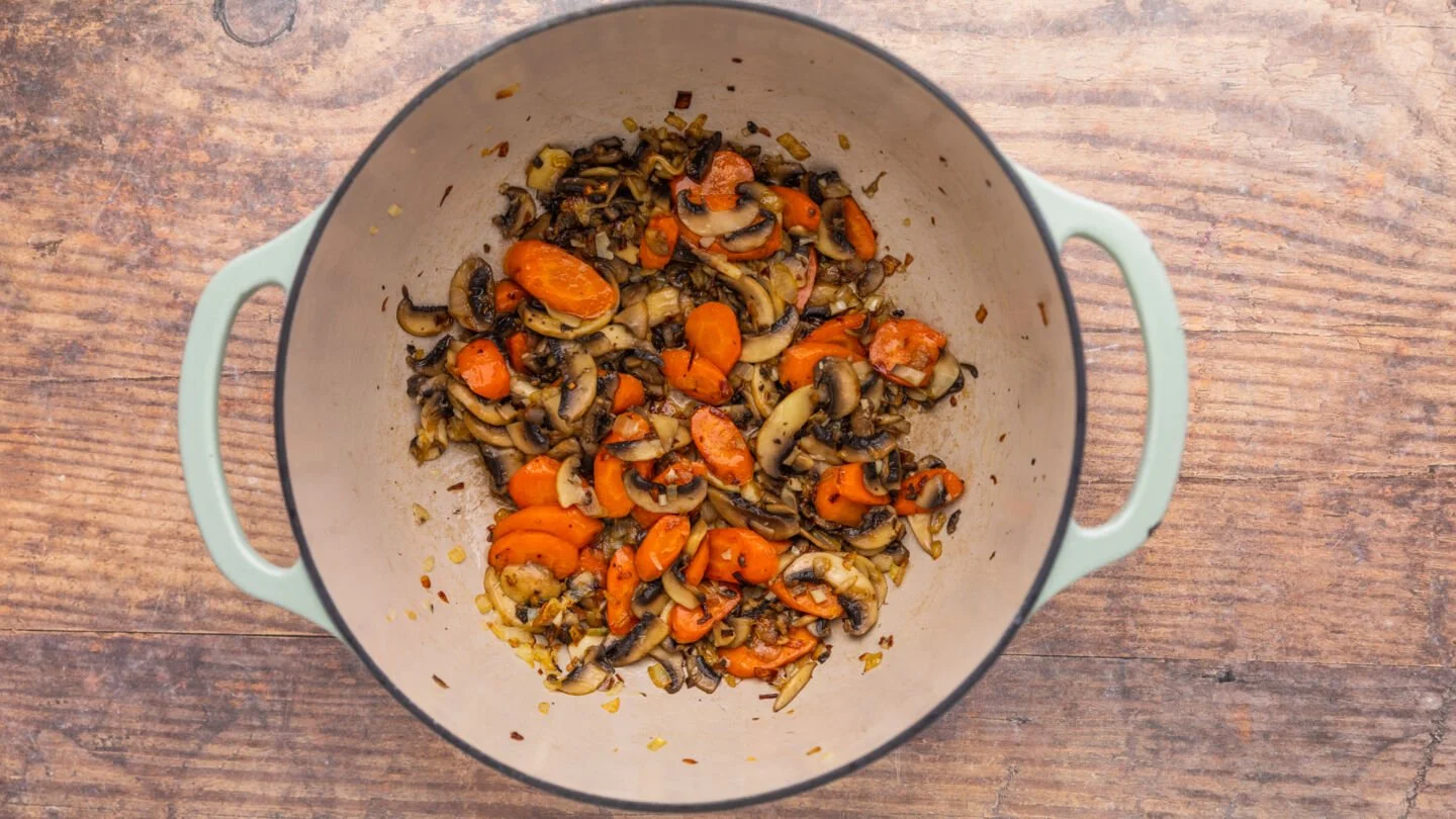 Melt butter in a Dutch oven or medium-sized pot over medium heat and brown the onions and carrots