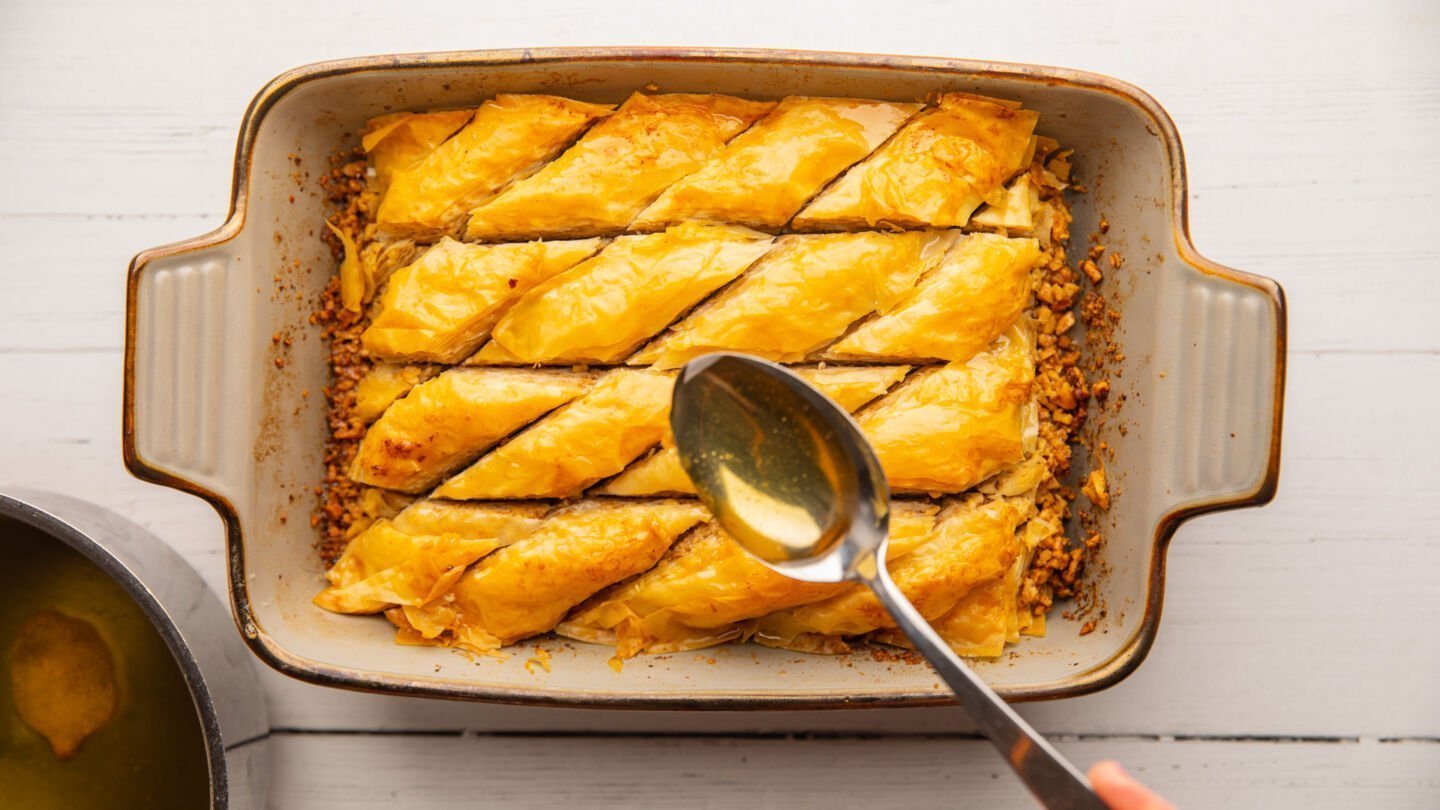 Remove the hot baklava from the oven and pour the cooled syrup over the top