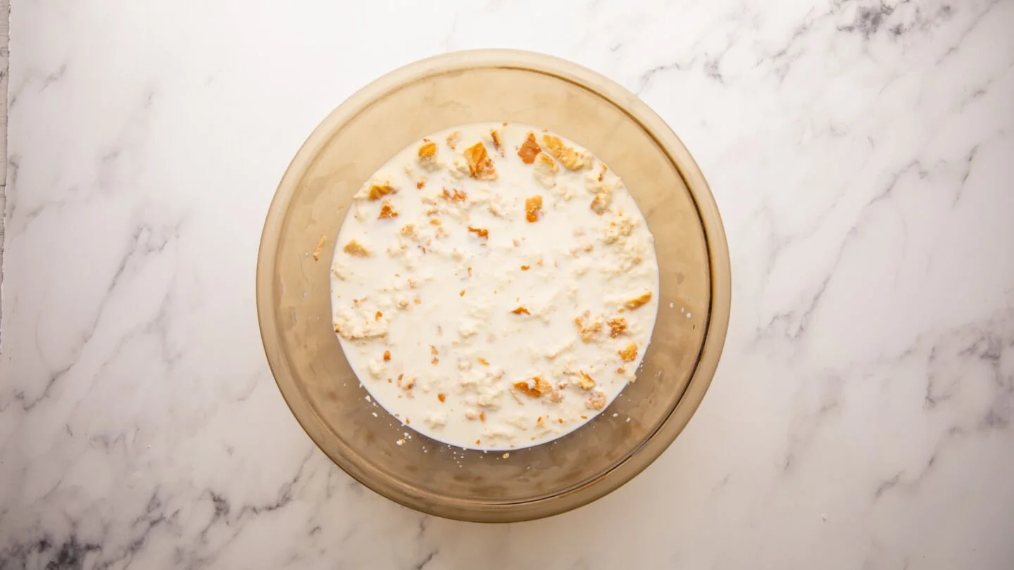 Put the cubed bread into a large bowl, pour the milk over, and crush the bread cubes with your hands