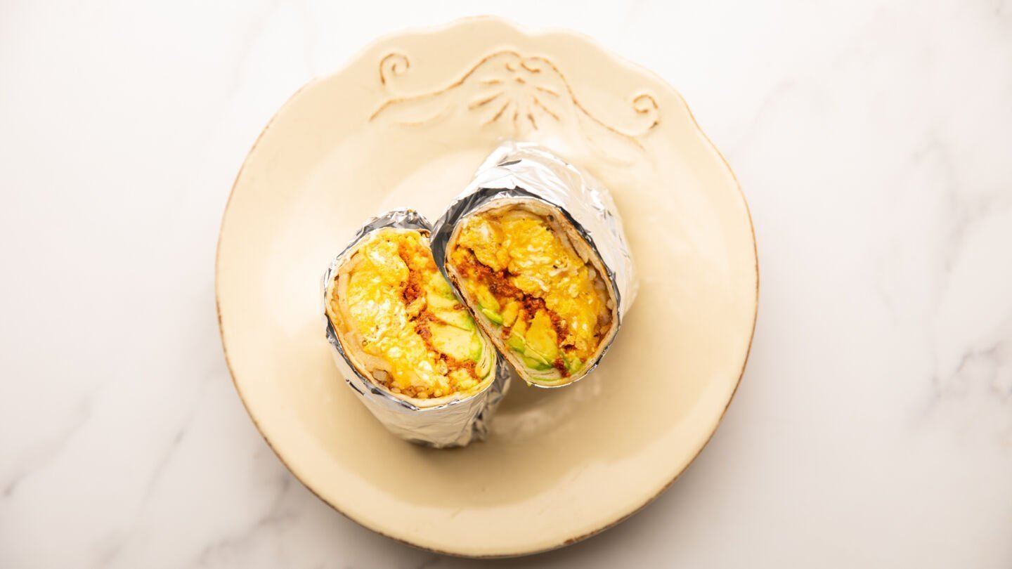 Transfer the cooked chorizo breakfast burritos to a chopping board, wrap each burrito in aluminum foil, and cut them in half