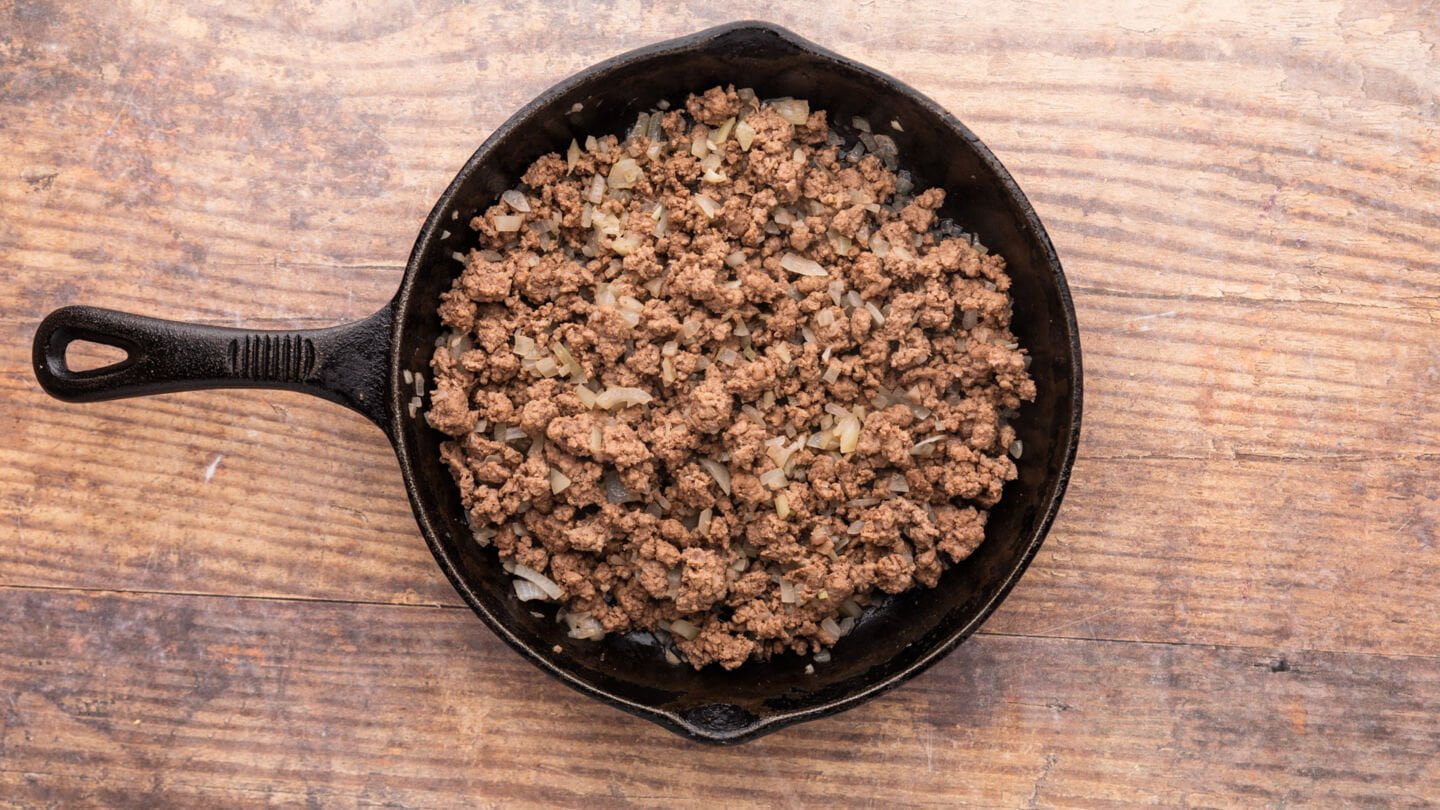 Set a large skillet over medium-high heat and saute the ground beef for a few minutes to brown before adding the garlic and onion