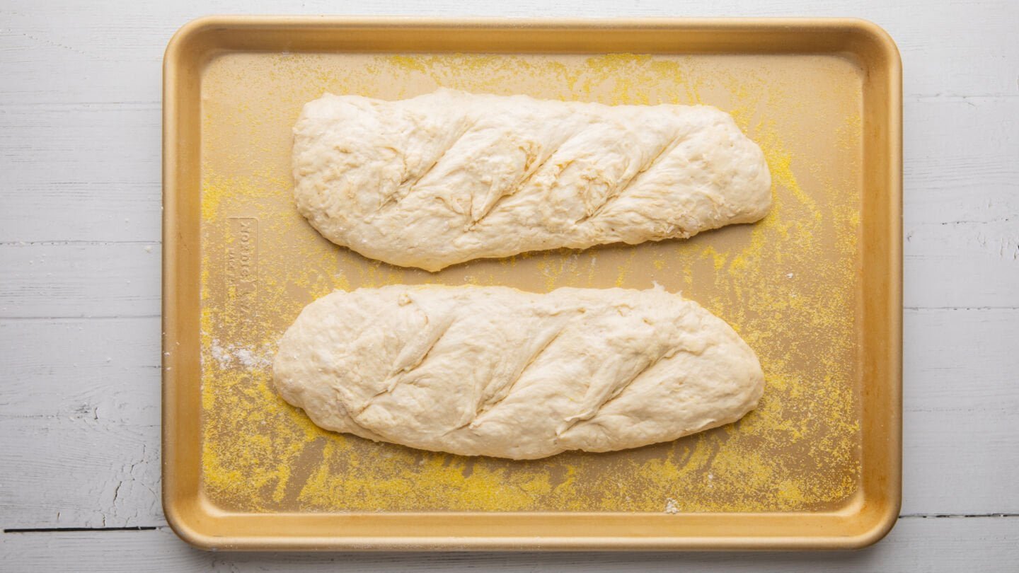 Once the loaves have risen slightly, score them across the top (½ inch deep) with a sharp knife or blade