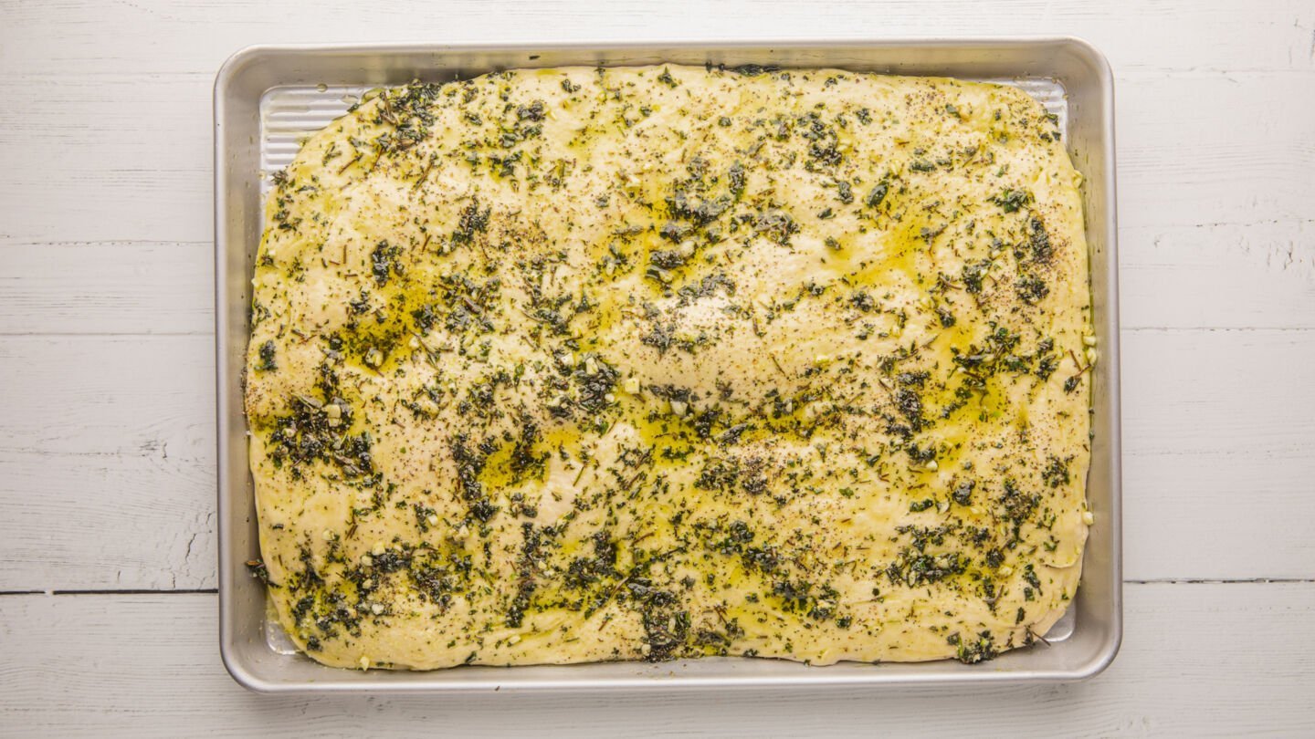 Spread the garlic and herb olive oil over the top of the focaccia using a pastry brush