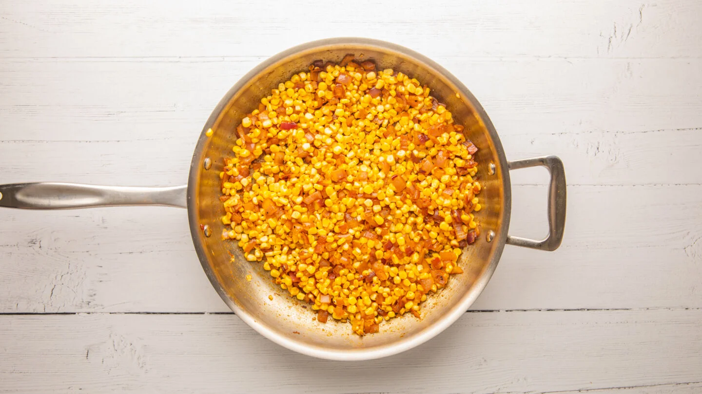 Add the corn, minced garlic, and 1 teaspoon of the spice mix to the skillet and season with salt and pepper, cooking for 5 minutes until the corn softens