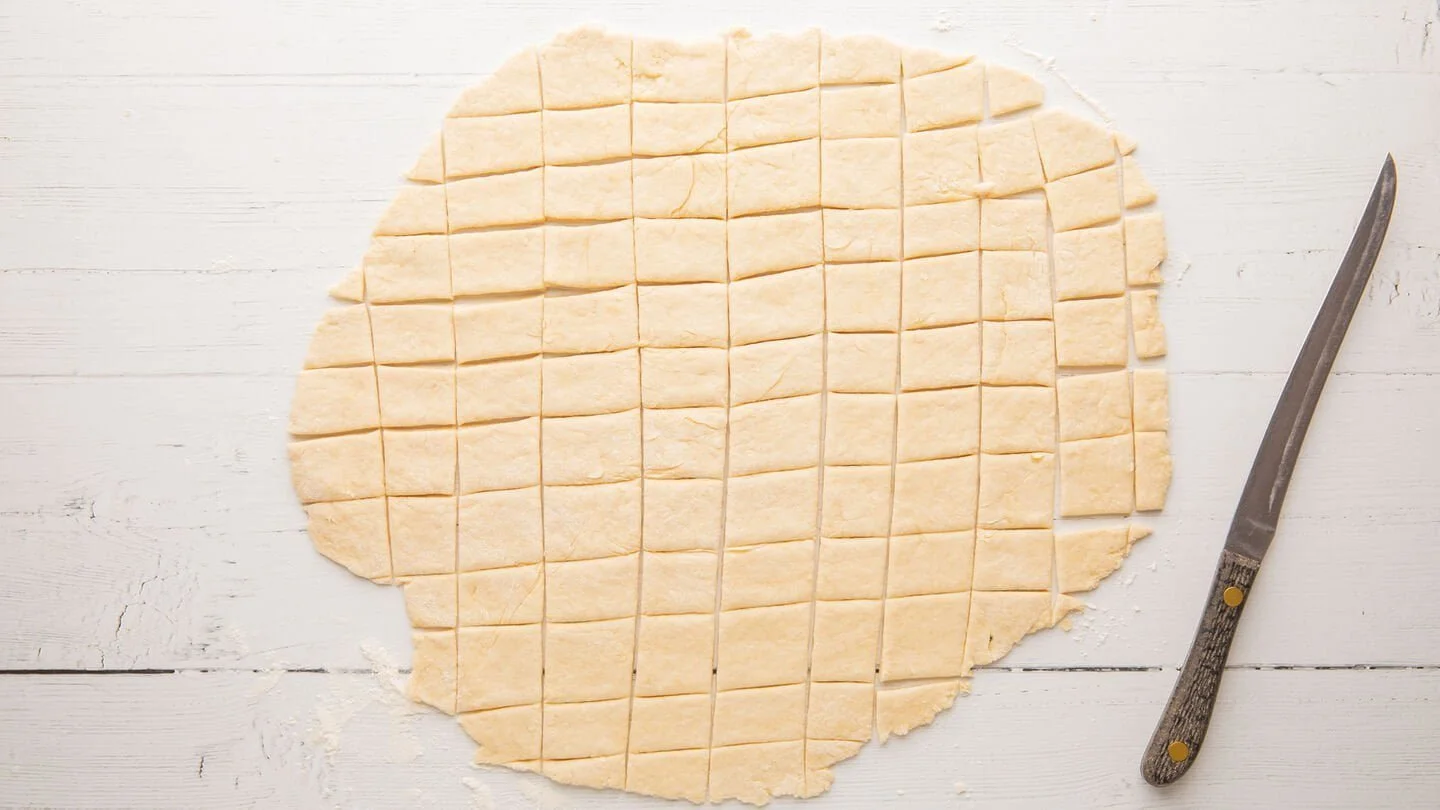 Roll the dough on a lightly floured surface to around ⅛ inch thickness and cut it into squares around 2 inches in size.