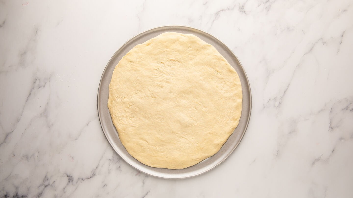 Roll out your pizza dough to fit the pizza pan.