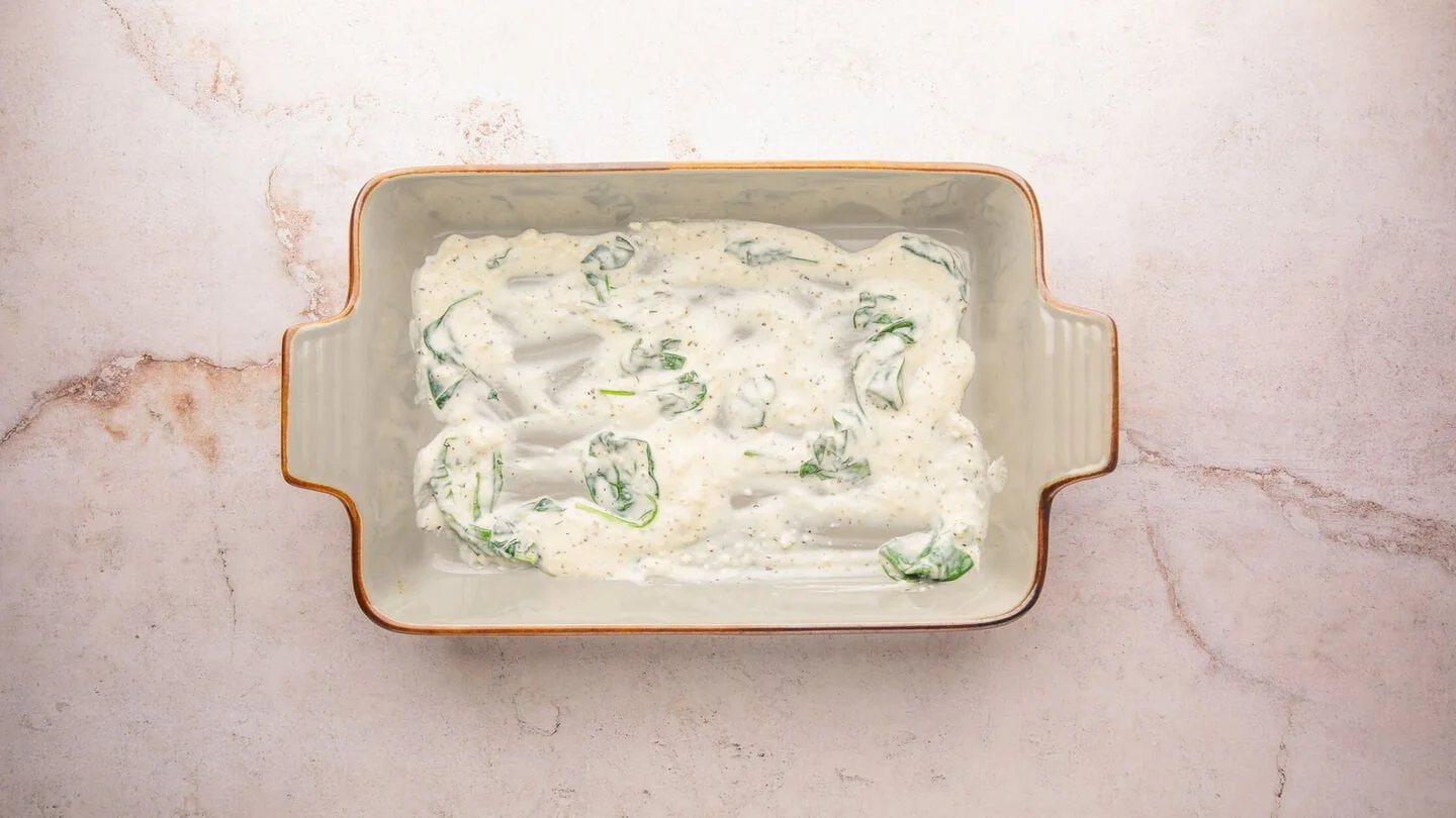 white lasagna sauce at bottom of baking dish